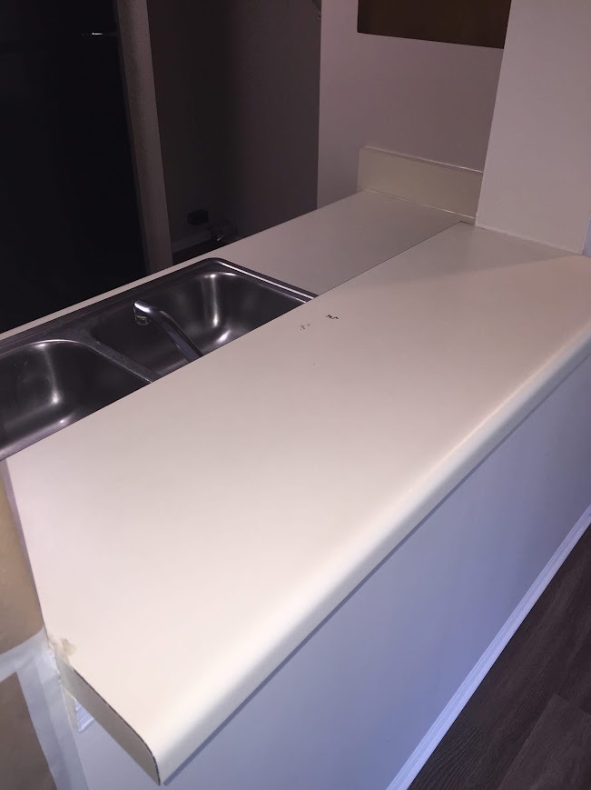 Worn white laminate kitchen countertop before refinishing
